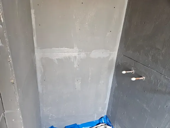 Bathroom stripped back to bare plastered and boarded walls with pipework left exposed before tiling.