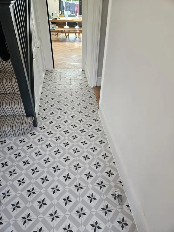 Hallway finished in black and white patterned floor tiles running from the front door through to the rear room.