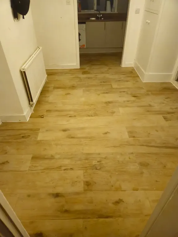 Finished wood-effect plank floor running through the kitchen and dining area and out through the doorway.