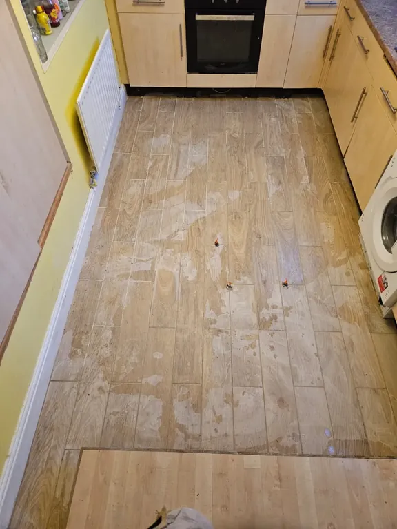 Wood-effect plank tiles laid the full length of a galley kitchen and cut in around the units and appliance space.
