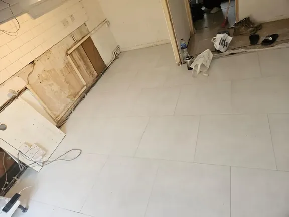 Completed large-format porcelain floor running through the kitchen with even joints and clean cuts to the walls.