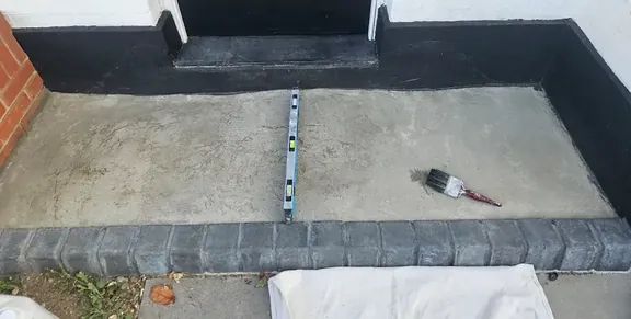 Bare concrete front path and step at the entrance to a house, levelled and ready for tiling.