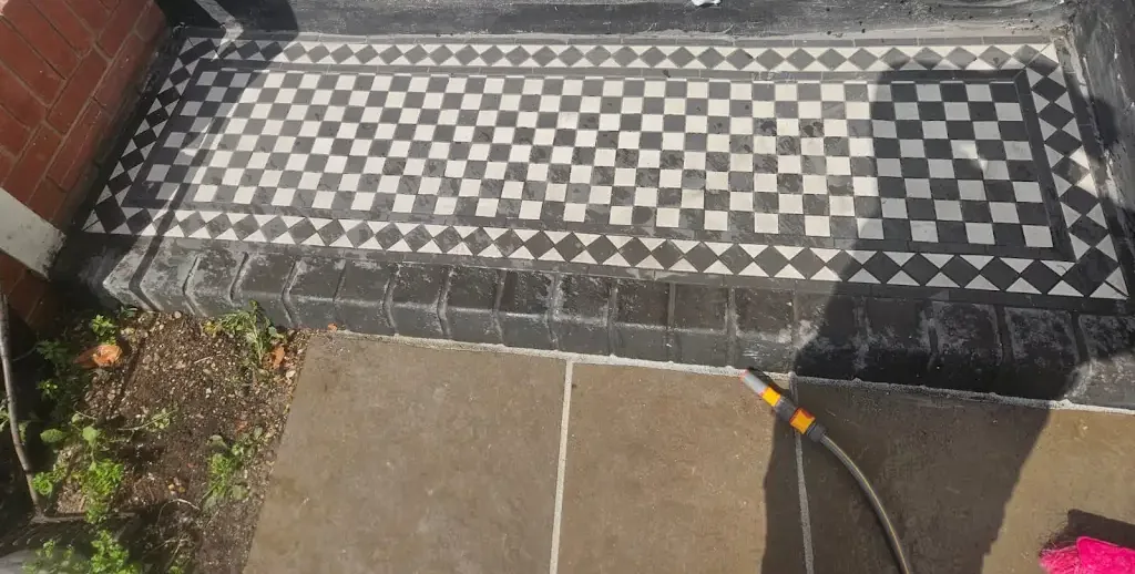 Front path laid in black and white geometric Victorian-style tiles with a patterned border running up to the front door.